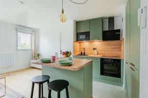 a kitchen with green cabinets and two bar stools at Le Cocon d'Achères in Achères