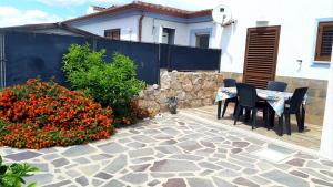 a patio with a table and chairs and some flowers at P I -G Ó 's HOUSE in Budoni