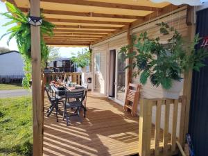 a wooden deck with a table and chairs on it at MOBIL-HOME "B27" tout confort avec piscine & lave-linge gratuits in Mimizan