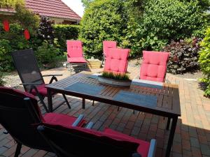 a patio with a table and four pink chairs at Wattliebe Burhave in Burhave