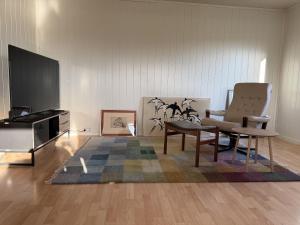 a living room with a tv and a chair and a table at Charming house close to Lekens in Skullbru