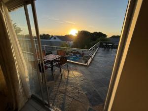 a balcony with a table and chairs and the sunset at Golden Feathers Lodge in Cape Town