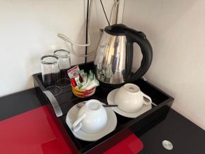 a tea pot and two cups on a black table at Golden Feathers Lodge in Cape Town