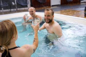 a man holding a glass of wine in a swimming pool at STF Korrö Gårdshotell in Linneryd
