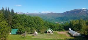 a farm with a greenhouse and mountains in the background at Mountain house"LISIN"Bradina Konjic in Konjic