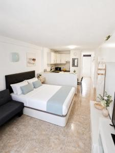 a bedroom with a large white bed and a kitchen at 213 Borinquen Holiday in Costa de Adeje
