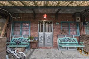een bakstenen gebouw met twee blauwe banken en een deur bij Just For Fun B&B in Pingxi