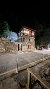 a large stone building with glass windows on a street at Casa rural Mirador, Balneario Histórico de Cortegada in Cortegada