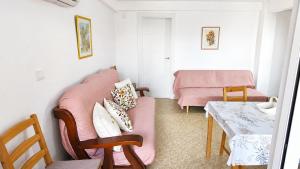 a living room with a pink couch and a table at Vacansis Apartamento Cullera Mar in Cullera