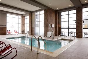 a large pool in a building with chairs and tables at Archer Hotel Boston/Burlington in Burlington