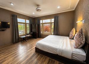 a bedroom with a bed and a desk and windows at Lidder view Resort - Best River side resort in Pahalgām