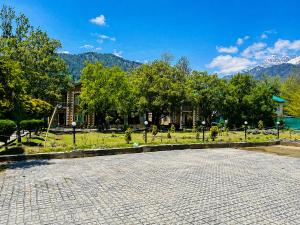 a park with trees and mountains in the background at Lidder view Resort - Best River side resort in Pahalgām +7 photos