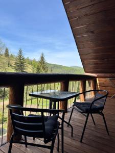 a table and two chairs on a deck with a view at Zrub House Карпати in Rozhanka Nizhnyaya