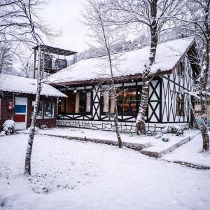 a house covered in snow with trees in front of it at River Retreat Resort in Pahalgām