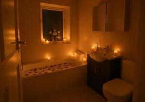 a bathroom with a tub and a sink and candles at Bliss Home in Harrow on the Hill