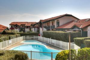 a villa with a swimming pool in front of a house at Appartement Santocha in Capbreton