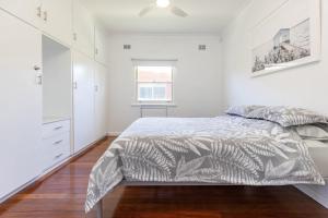 a white bedroom with a bed and a window at Summer Breeze Lake House in Forster