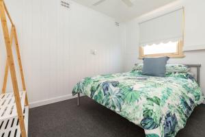 a bedroom with a bed with a green bedspread at Summer Breeze Lake House in Forster +30 photos