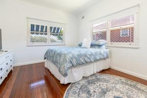 a bedroom with a bed and two windows at Summer Breeze Lake House in Forster