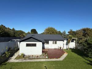 a white house with a fence and a yard at Otaihanga Getaway in Paraparaumu