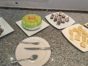 a table with plates and utensils and desserts at Grand Halomy Megan in Sharm El Sheikh