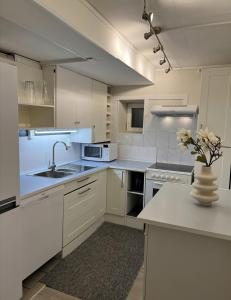 a kitchen with white cabinets and a vase of flowers at Arya villa in Bergen