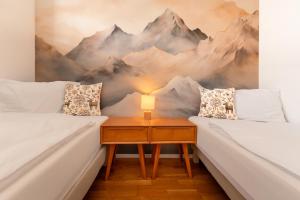a room with two beds and a nightstand with a mountain mural at RIVER Apartment in Andermatt