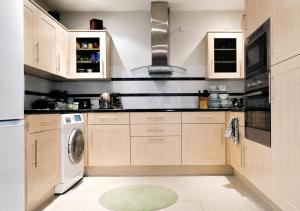 a kitchen with wooden cabinets and a washer and dryer at Bliss Home in Harrow on the Hill