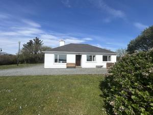 a white house with a bench in a yard at Waterside Cottage, Cashel in Galway