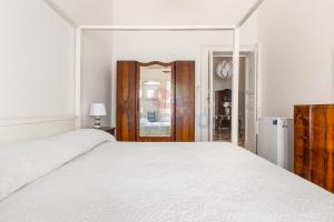 a white bedroom with a large bed and a refrigerator at Palazzo del Borgo Salentino in Acquarica del Capo