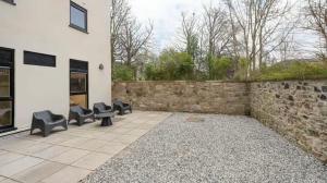 a patio with chairs next to a stone wall at Straits Place in Edinburgh in Edinburgh