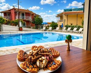 a plate of food on a table next to a pool at Elli Marina Studios & Apts Benitses Mare in Benitses