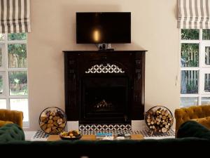 a living room with a fireplace with a television above it at Romantic Boutique Cottage in upper Hogsback in Hogsback