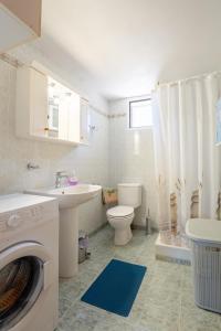 a bathroom with a toilet sink and a washing machine at Zante's Northern View in Koríthion