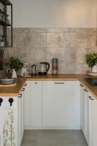a kitchen with white cabinets and a tile wall at Roubenka Bohéma in Verneřice