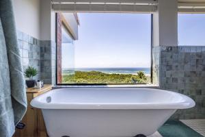 a bath tub in a bathroom with a large window at Begha 180 Beach House in Begha Mouth