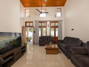 a living room with two couches and a flat screen tv at The Calm boutique Villa in Ahangama