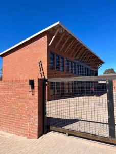 a brick building with a fence in front of it at Red Robin Guesthouse in Postmasburg