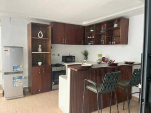 a kitchen with wooden cabinets and a counter with chairs at Immeuble cgk in Cocody