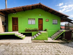 a green house with stairs in front of it at Vista das Montanhas in Monte Verde