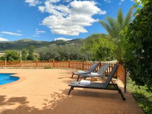 a couple of chairs sitting next to a pool at Cortijo El Búho - Casa rural con piscina privada en Montefrío in Montefrío
