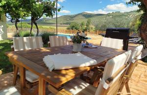 a wooden table with white chairs around it with a view at Cortijo El Búho - Casa rural con piscina privada en Montefrío in Montefrío +18 photos