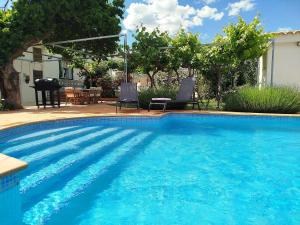 a blue swimming pool with two chairs and a table at Cortijo El Búho - Casa rural con piscina privada en Montefrío in Montefrío
