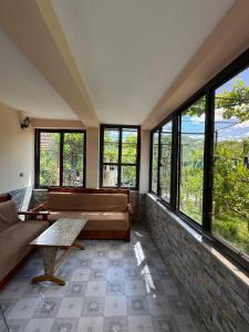 a living room with couches and a table and windows at Guest House Ajasllari in Çorovodë