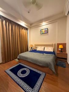 a bedroom with a large bed and a blue rug at ITC Grand Stay in Greater Noida