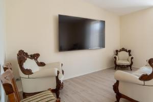 a living room with two chairs and a flat screen tv at Viscuso House B&B in Aci Castello