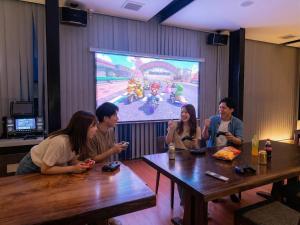 a group of people sitting around a table in front of a video game at SENJA Dewata in Mitoyo