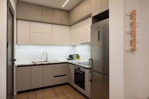 a kitchen with white cabinets and a sink and a refrigerator at Kitron Blue Seaside Luxury Apartment in Agios Nikolaos