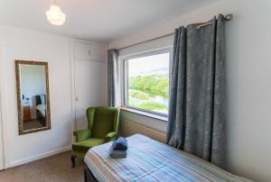 a bedroom with a green chair and a window at Sneem Townhouse in Sneem