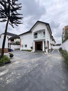 a white house with a tree in the driveway at Casa Midelle in Alagbado